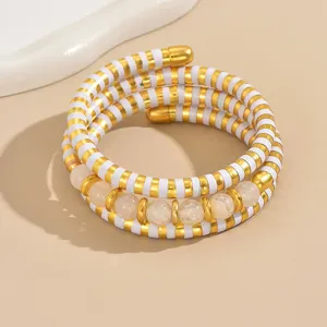 Vue de détail d'un bracelet enveloppant multicouche avec des rayures dorées et des perles.