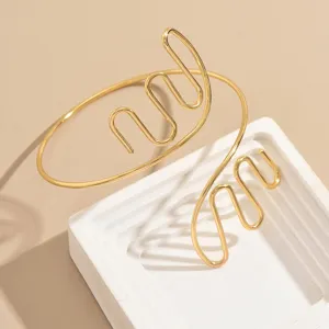 Vista di dettaglio di un bracciale da braccio aperto in filo astratto dorato, gioiello trendy.
