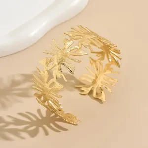 Bracciale rigido aperto con design a foglia traforata, gioiello dorato di tendenza.