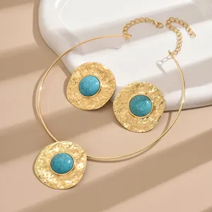 Detail view of the exaggerated vintage turquoise choker necklace and earrings set with textured gold.
