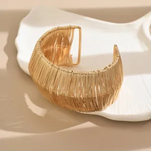 Detailed shot of a wide gold open cuff bracelet with unique wire wrapped hollow design.