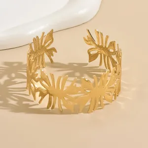 Bracciale rigido aperto dorato con intricato design traforato, elegante gioiello da polso.
