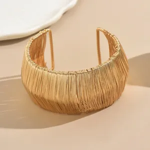 Exaggerated wide gold metal cuff bracelet, modern wire-wrapped hollow fashion open bangle jewelry.