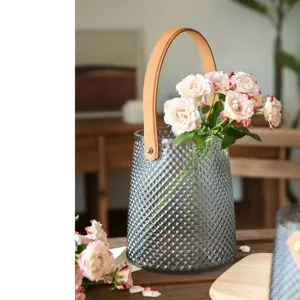 Transparent glass vase with leather handle and roses, modern home decor for living room.