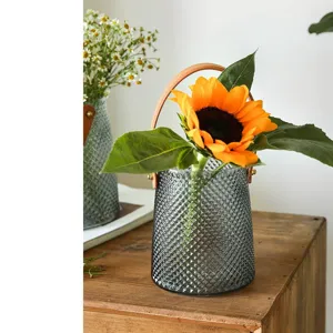 Elegant glass flower vase with brown leather handle, perfect for modern home decor and floral art.