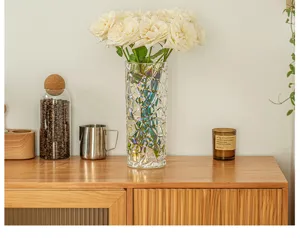 Detail shot of a clear textured glass vase with white roses on a wooden table, cozy home decor.