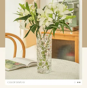 Detailed view of transparent crystal faceted glass vase with fresh white lilies on dining table.