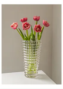 Detailansicht der klaren, gerippten Glasvase mit zarten rosa Tulpenblüten im Inneren.