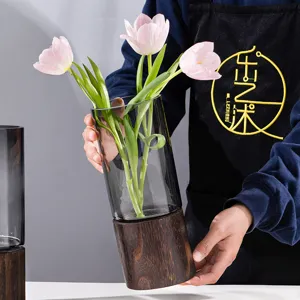 Modern grey glass vase with dark wood base, elegant floral arrangement for home decor.