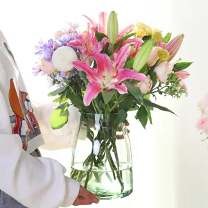 Moderno florero de vidrio verde transparente para arreglos florales elegantes en la mesa.