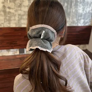 Grey knit hair scrunchie with pink ruffle trim, elegant hair tie accessory for women.