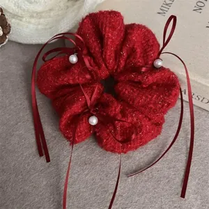 Détail de chouchou en tweed rouge, élégant ruban et décor de perles, accessoire festif.