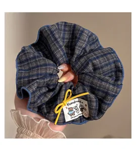 Λεπτομερής όψη μεγάλης καρό scrunchie μαλλιών με χειροποίητη ετικέτα και κορδόνι.