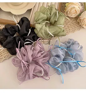 Κοντινή λεπτομέρεια scrunchie μαλλιών οργάντζα με πέρλες και γλυκό φιόγκο για στυλ.