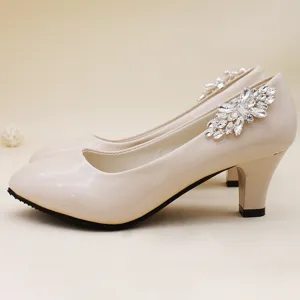 Zapatos de tacón alto de charol beige con decoración floral de cristal para novia.