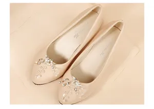 Detail shot of beige pointed-toe heels with sparkling crystal rhinestone floral shoe clips.