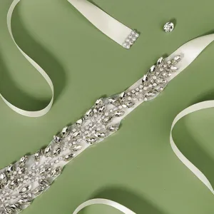 Close-up detail of luxury bridal rhinestone sash belt with sparkling crystals on white ribbon.
