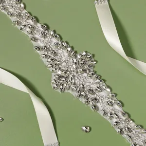 Luxurious rhinestone bridal belt detail, sparkling crystal beadwork on white satin sash.