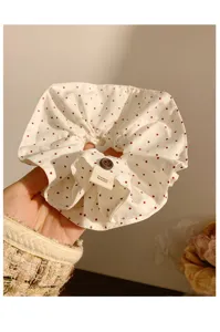 Primo piano di un elastico per capelli quadrato a pois bianchi in stile coreano con bottone.