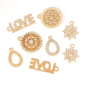 Gedetailleerde opname van gouden legering strass love letters en geometrische hangende bedels.