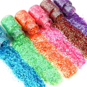 Primo piano dettagliato di paillettes esagonali colorate versate da piccoli barattoli artigianali.