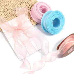 Detailansicht von bunten Organzaband-Rollen und rosa Schleife fuer Geschenkverpackung