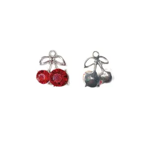 Close-up detail of silver alloy cherry charm pendant with red zircon and cute bow design.