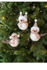 Detailed shot of cute Christmas bird ornaments with champagne hats and fluffy scarves on tree.