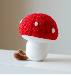 Primo piano dettagliato del peluche a fungo rosso e bianco, morbida e accogliente decorazione.