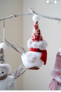 Close-up detail of a cute Christmas bird pendant with knit hat and plush scarf for holiday tree decor.