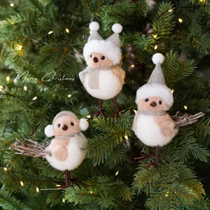 Christmas tree bird decorations with champagne hats and scarves hanging on a holiday tree.