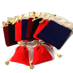 Detailed view of colorful velvet drawstring bags with gold borders for jewelry packaging.