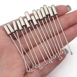 Close-up van zilverkleurige DIY brochespelden en accessoires netjes gepresenteerd in de hand.