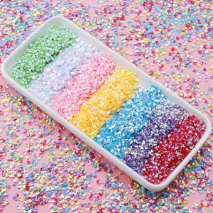 Primo piano dettagliato di paillettes olografiche colorate per nail art in vassoio bianco con pezzi.