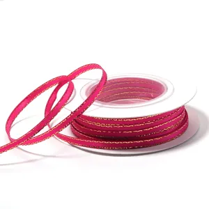 Detail shot of pink polyester ribbon with gold edge on spool for DIY gift packaging bows.