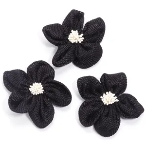 Closeup of handmade black burlap five-petal flower accessory with white stamen details.