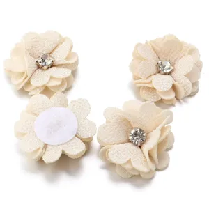 Handmade beige fabric flower accessories with sparkling rhinestones, detailed DIY craft supplies.