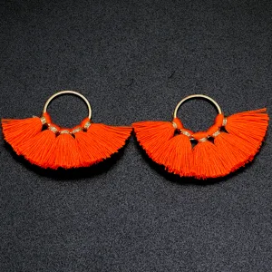 Nahaufnahme von orangefarbenen Quasten mit Metallring als handgemachtes Schmuckzubehör.