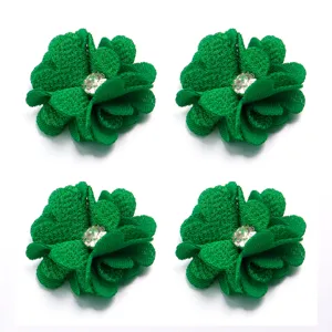 Close-up detail of green four-petal linen flower DIY accessory with rhinestone center.