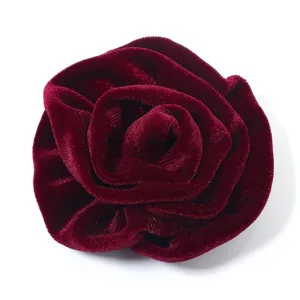 Close-up of a burgundy velvet rose flower accessory, showing soft fabric texture and details.