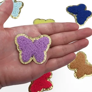 Dettaglio della toppa a farfalla in ciniglia con consistenza soffice e bordo glitterato.