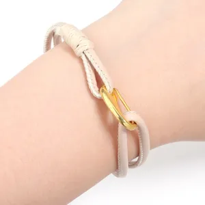 Close-up detail of the woven leather rope bracelet featuring a gold clasp on wrist.