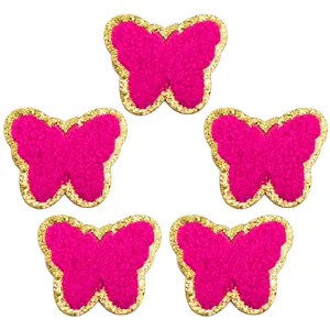 Vista dettagliata di toppe a farfalla in ciniglia rosa con bordi glitterati oro per il fai da te.