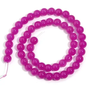 Primo piano di perline rotonde in vetro magenta brillante per accessori fai da te.