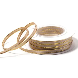 Detail shot of khaki polyester ribbon with metallic gold edge wound on a white plastic spool.