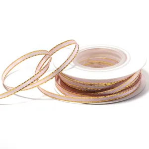 Pink polyester ribbon with gold trim detail for gift packaging, bows and DIY crafts.