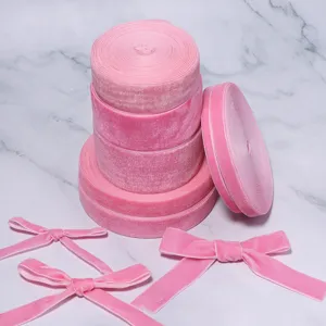 Detailaufnahme von rosafarbenen Samtbandrollen und süßen Schleifen für DIY-Haarspangen, Geschenke.