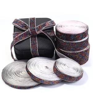 Colorful glitter metallic elastic ribbon rolls and gift box display for creative DIY crafts.