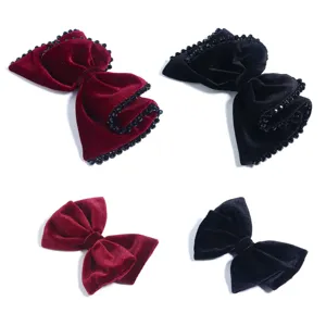 Vista dettaglio molletta capelli fiocco velluto, bordo perline strass e stile classico, nero e rosso.