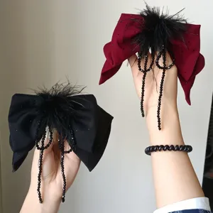 Vista dettagliata di eleganti fermagli per capelli a fiocco con piume nere e perline di cristallo.